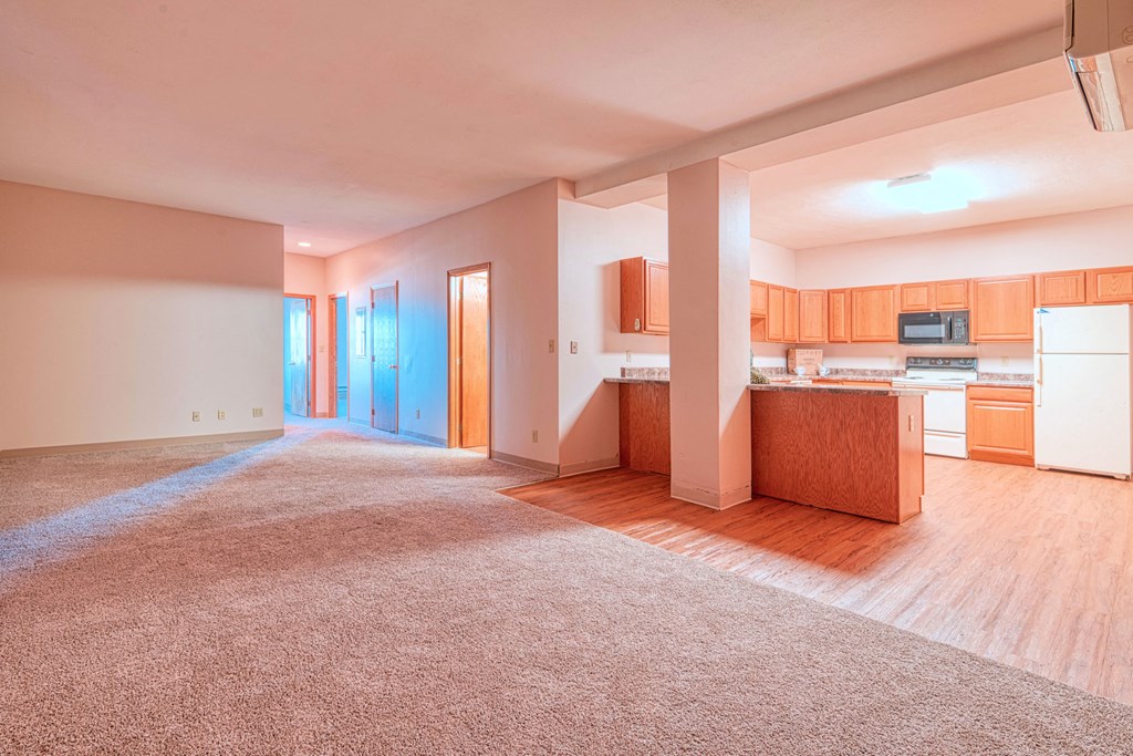 an empty living room and kitchen with wood flooring