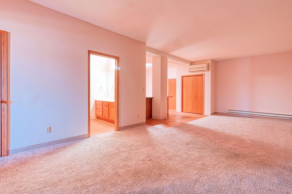 the living room and dining room of an empty house with carpeting and a door