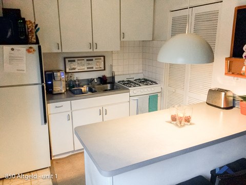 a white kitchen with a white table and a white refrigerator