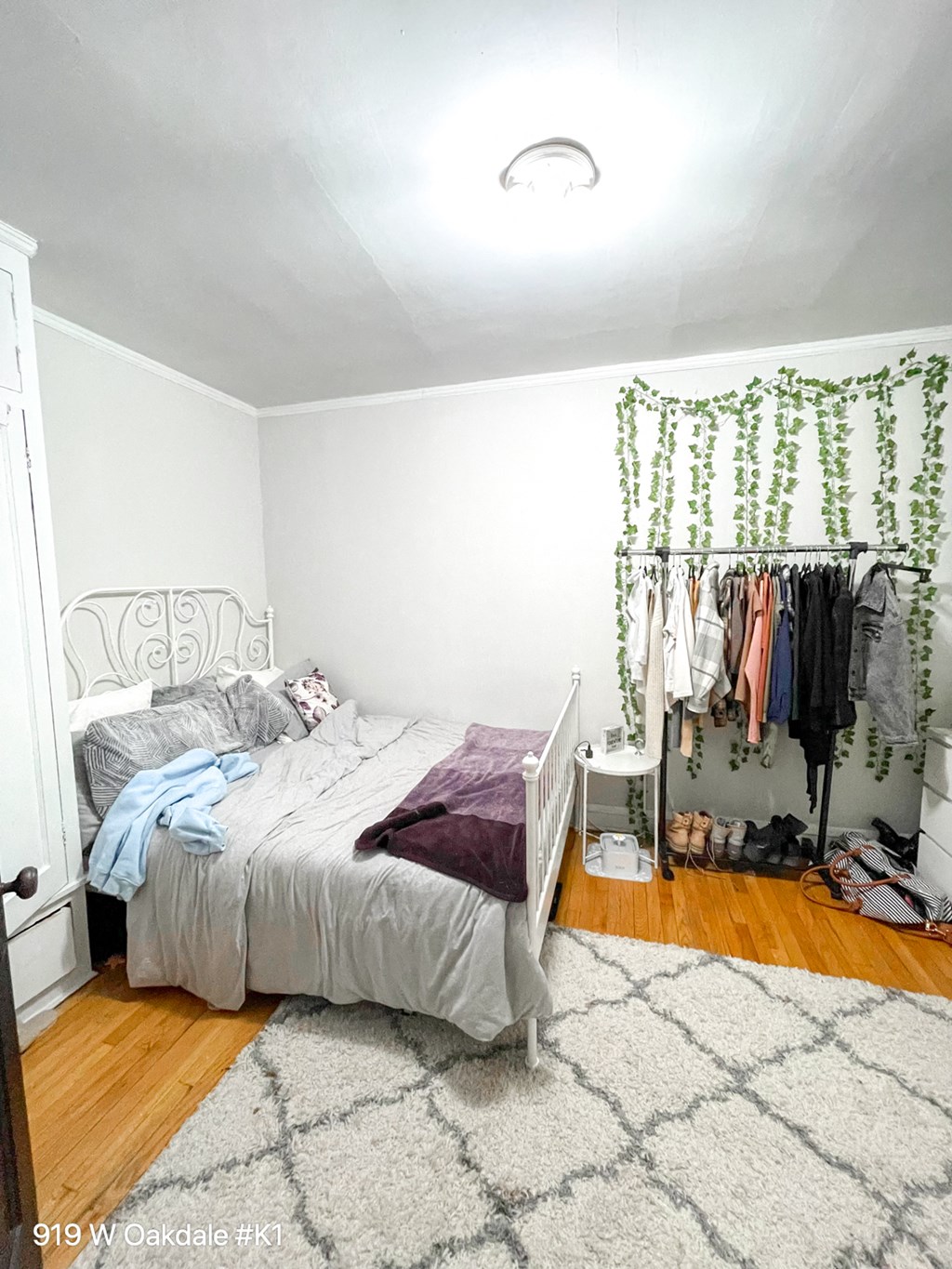 a bedroom with a bed and a closet with clothes hanging