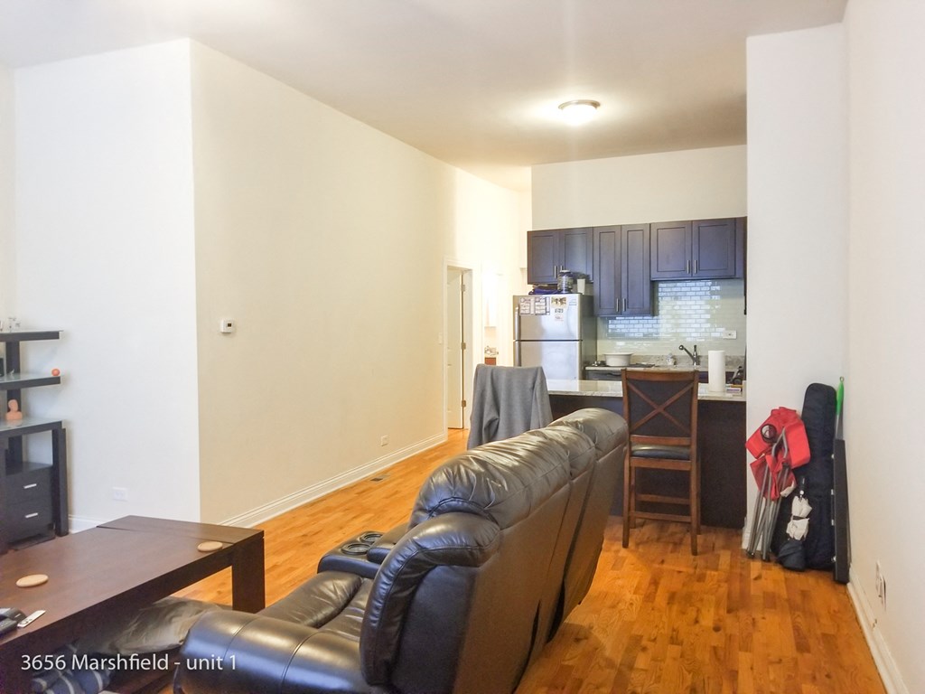 an empty living room with a leather couch and a kitchen