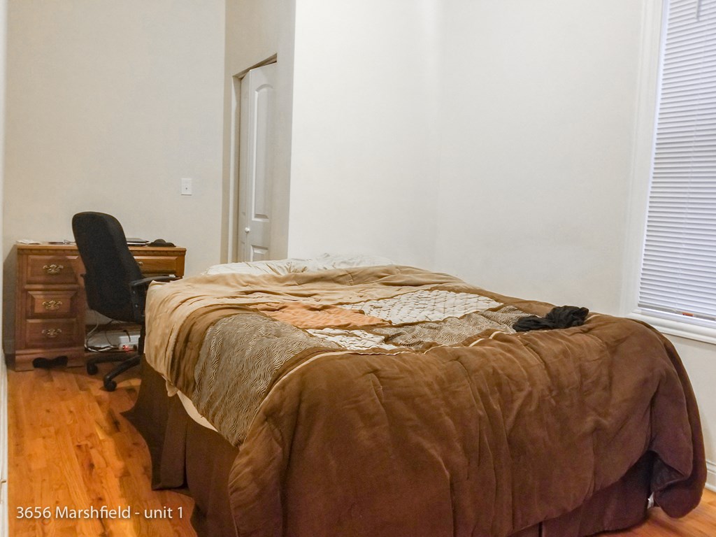 a bedroom with a bed and a desk and a chair