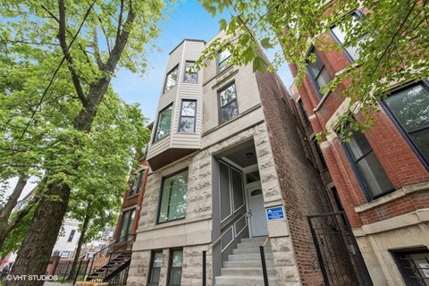 a condo building with stairs and trees in front of it