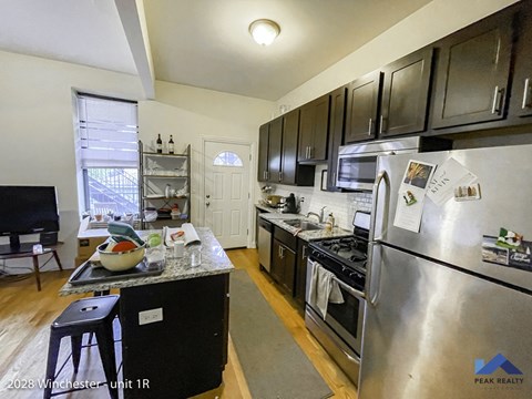 an open kitchen with stainless steel appliances and black cabinets