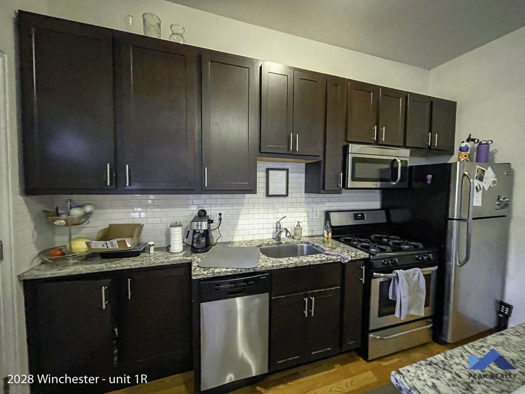 a kitchen with black cabinets and stainless steel appliances