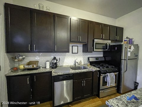 a kitchen with black cabinets and stainless steel appliances
