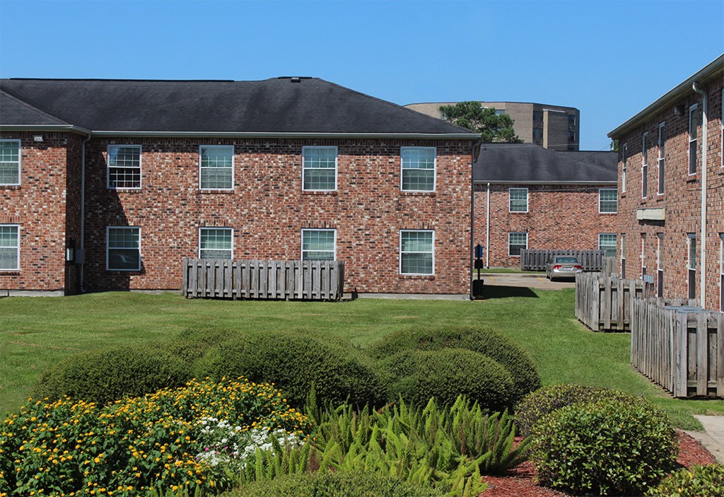 a brick building with a lawn and garden in front of it