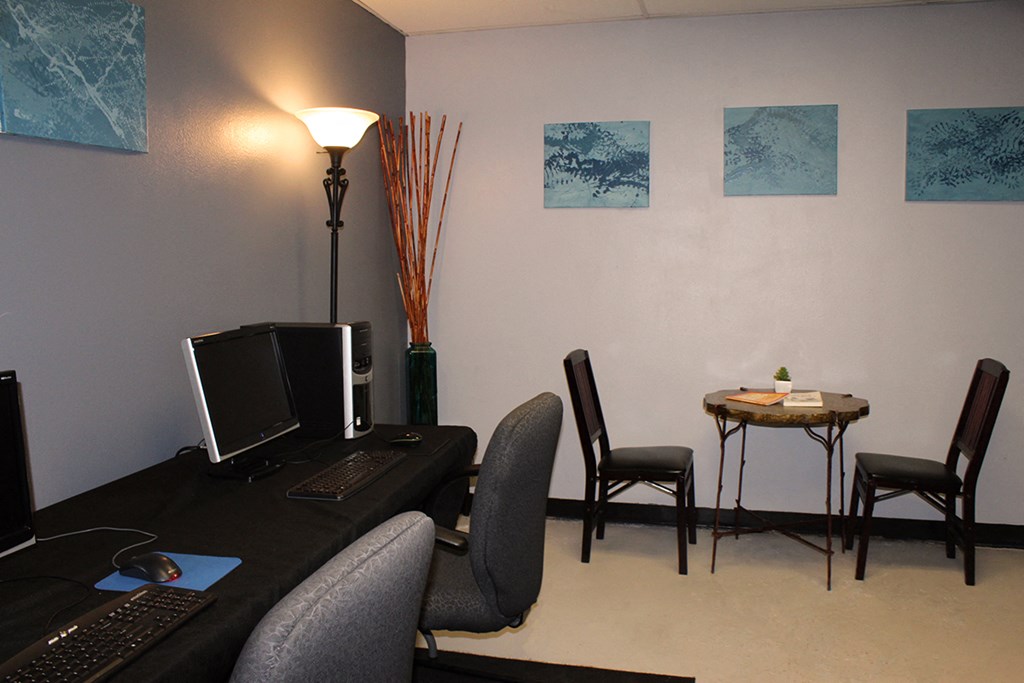 an office with a computer desk and a table with chairs