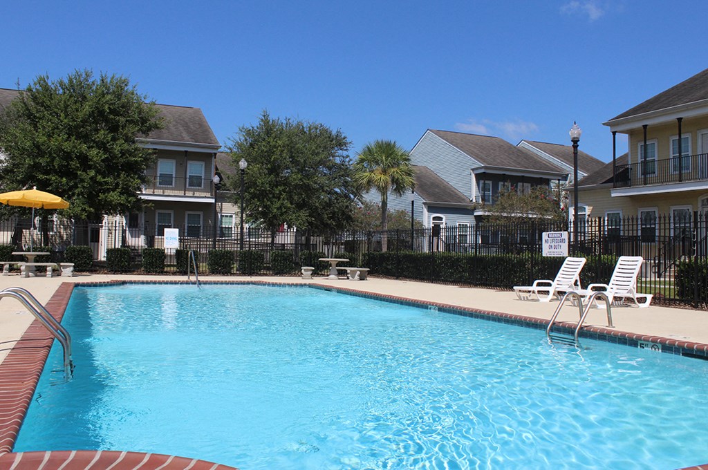 a swimming pool with chairs and houses in the background