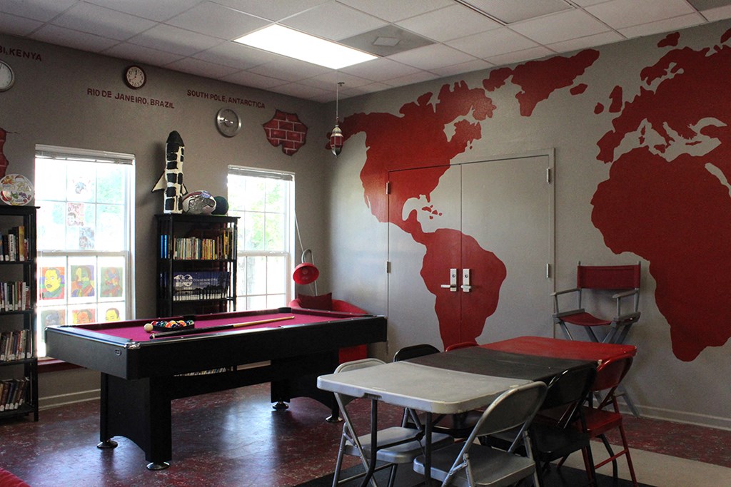 a game room with a pool table and a map of the world on the wall