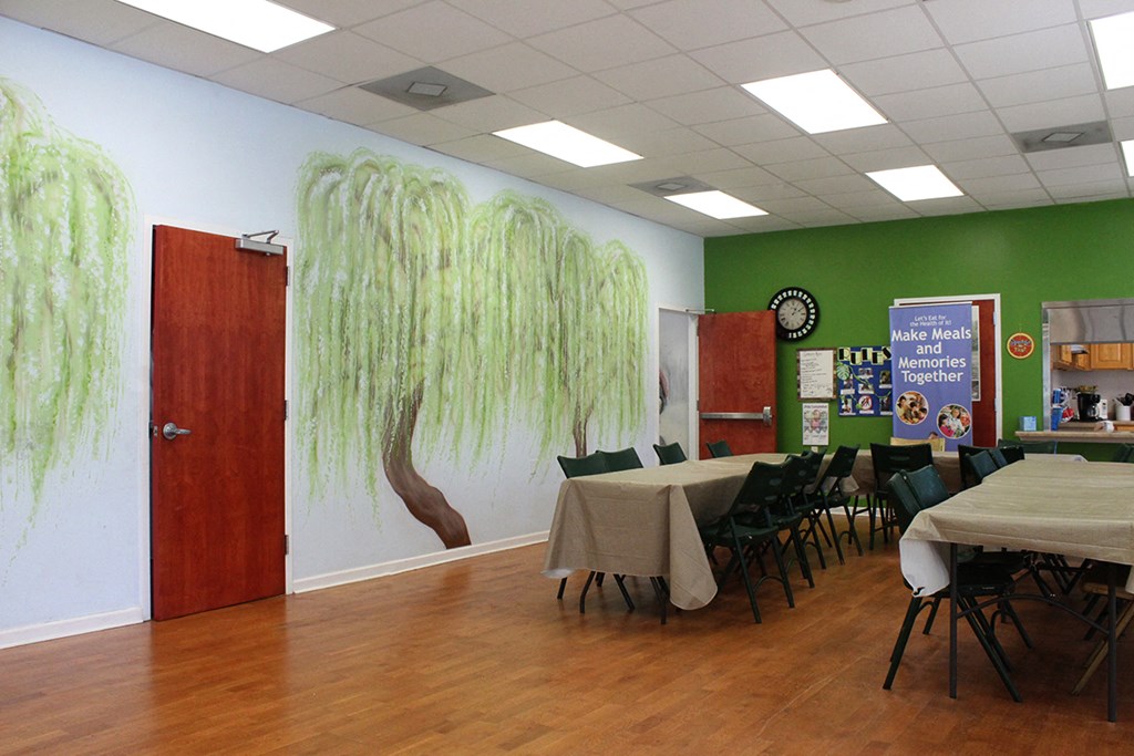 a dining room with tables and chairs and a wall mural of trees