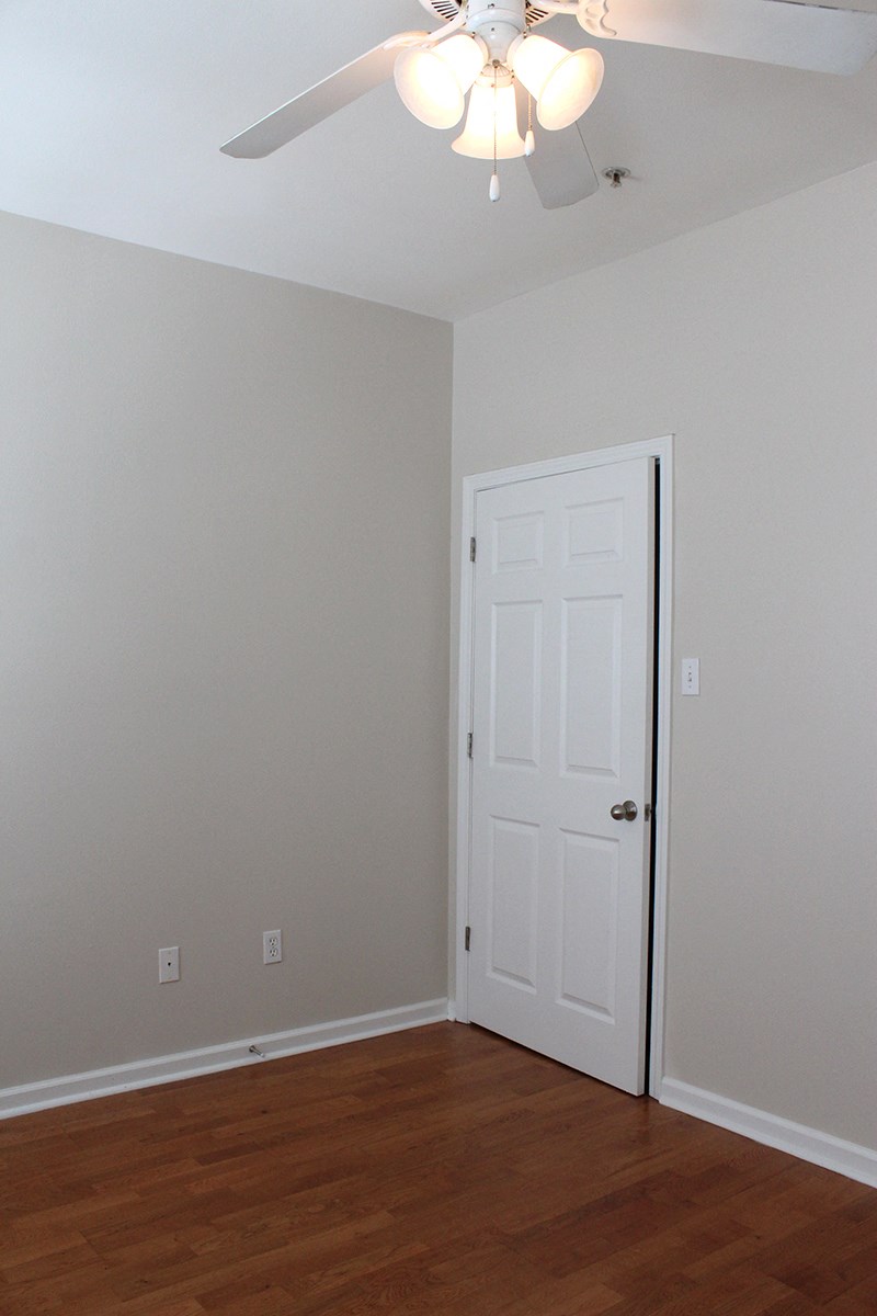 an empty room with a white door and a ceiling fan