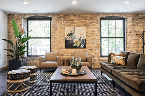 A living room with a brown couch, a coffee table, and a large painting on the wall.