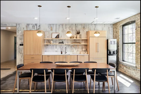 A kitchen with a table and chairs in front of a brick wall.