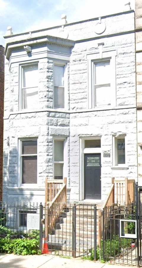 A white building with a black door and a black fence.