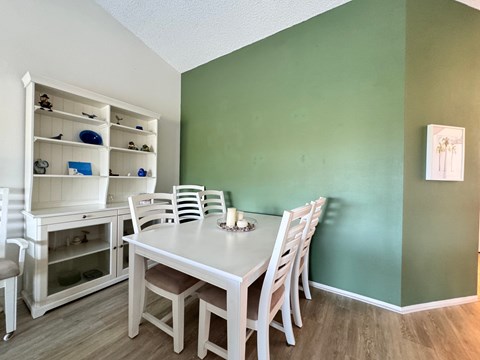 a dining room with a white table and chairs and a green wall