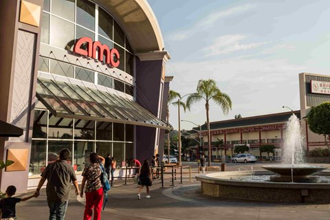 A family is walking in front of the AMC cinema.