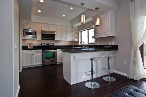 A kitchen with a black counter top and white cabinets.