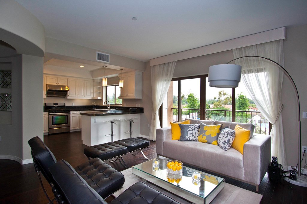 A modern living room with a grey couch and a glass coffee table.
