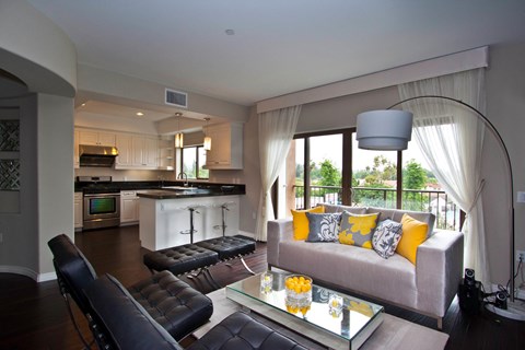 A modern living room with a grey couch and a glass coffee table.