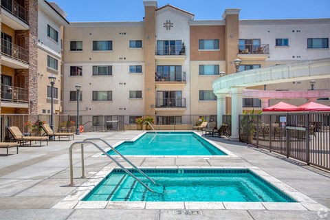 A swimming pool in front of a multi-story apartment building.