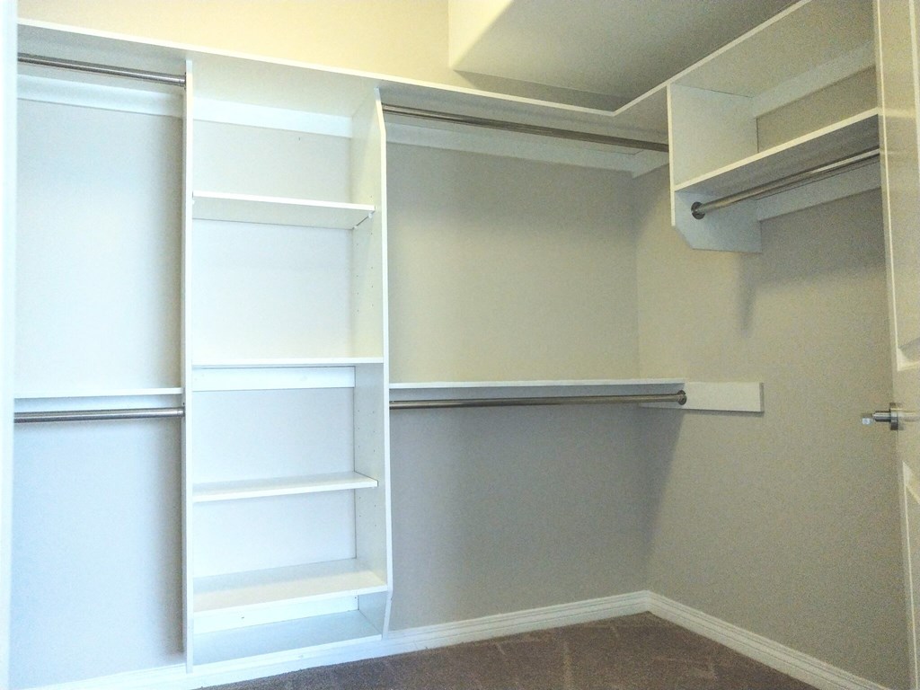 A white closet with shelves and a door.