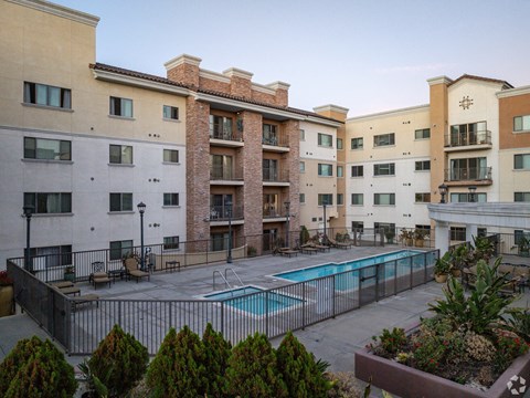 A large apartment complex with a pool in the courtyard.