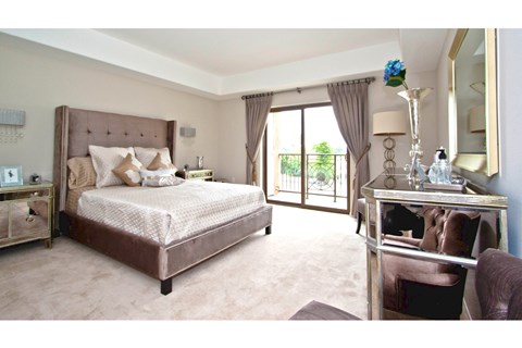 A bedroom with a large bed, a desk, and a chair.