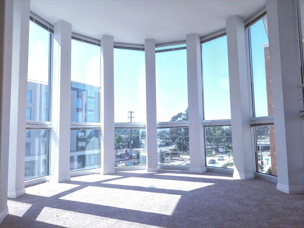 A sunny day in a room with large windows and white columns.