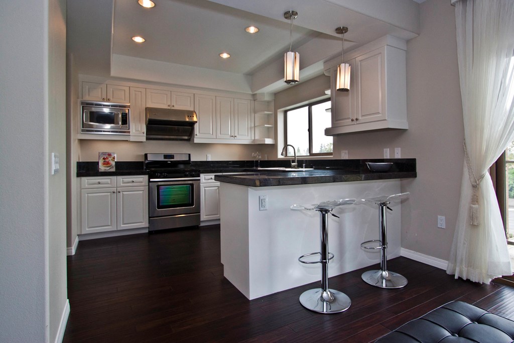 A kitchen with a black counter top and white cabinets.