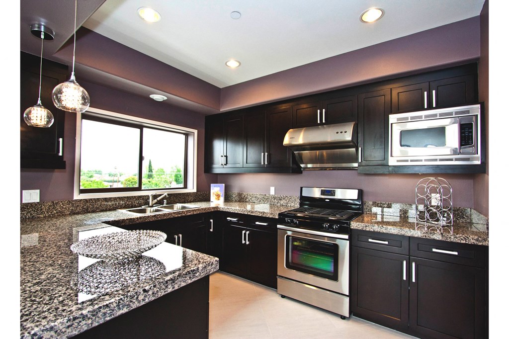 A kitchen with black cabinets and granite countertops.