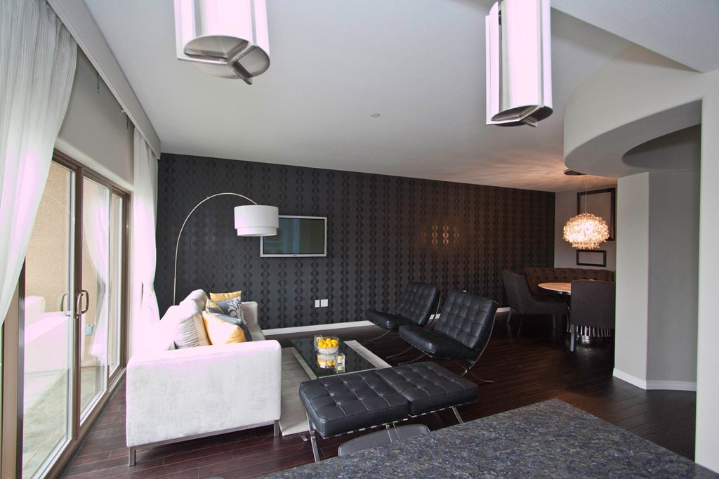 A modern living room with a white couch and black chairs.