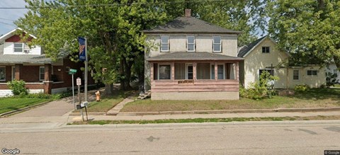 A house with a porch and a flag on a pole in front.