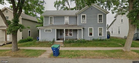 A blue house with a tree in front.