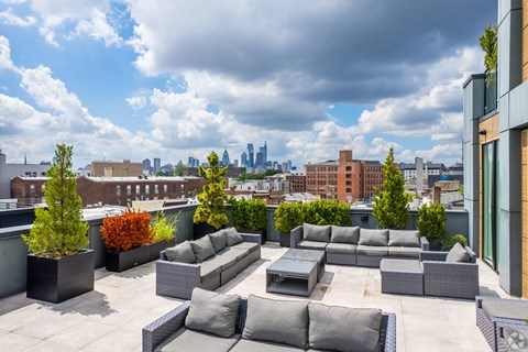 A rooftop patio with grey furniture and a view of the city skyline.