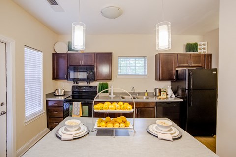 a kitchen with black appliances and a counter with fruit on it