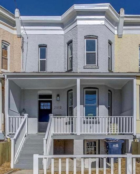 A two-story house with a blue door and white railings.