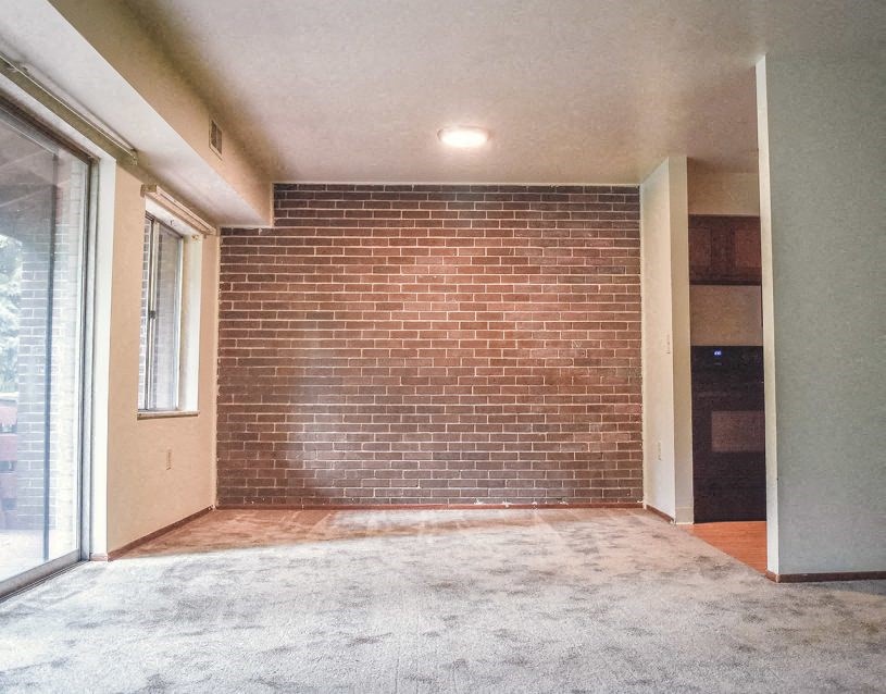 an empty living room with a brick wall