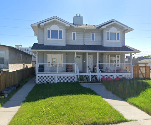 A two-story house with a white porch and a grey roof.