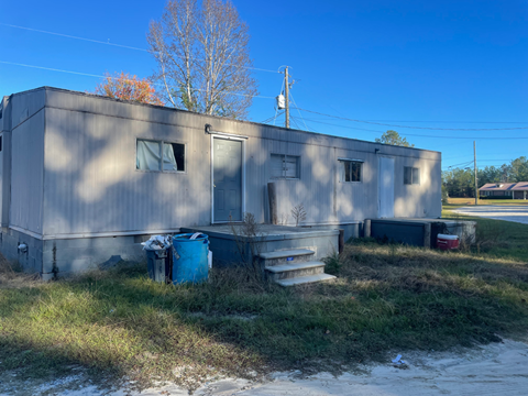 A grey building with a blue barrel in front of it.