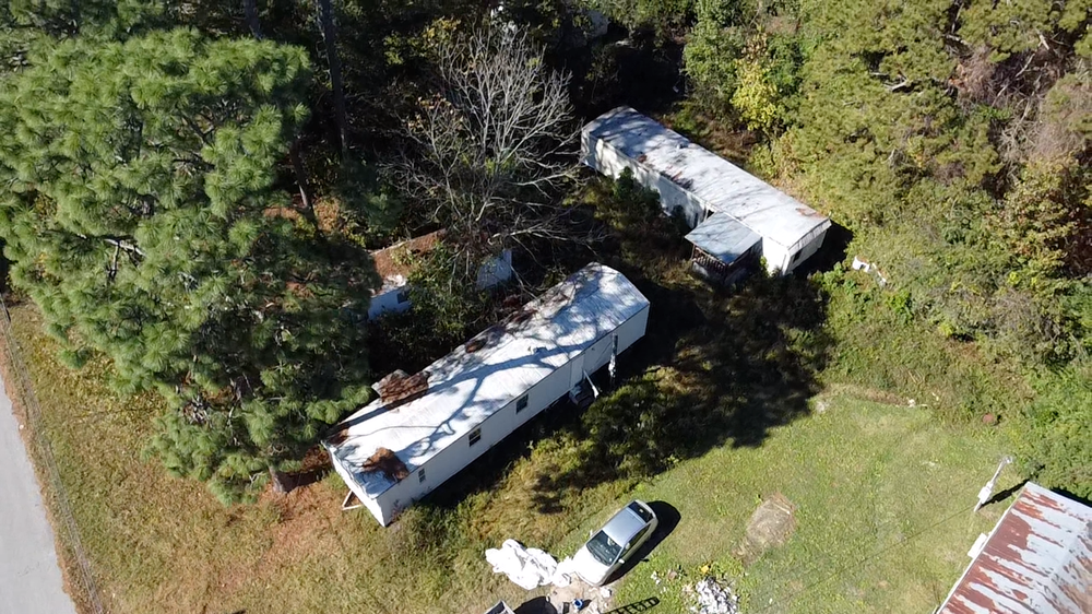 A white RV is parked in a grassy area next to a tree.