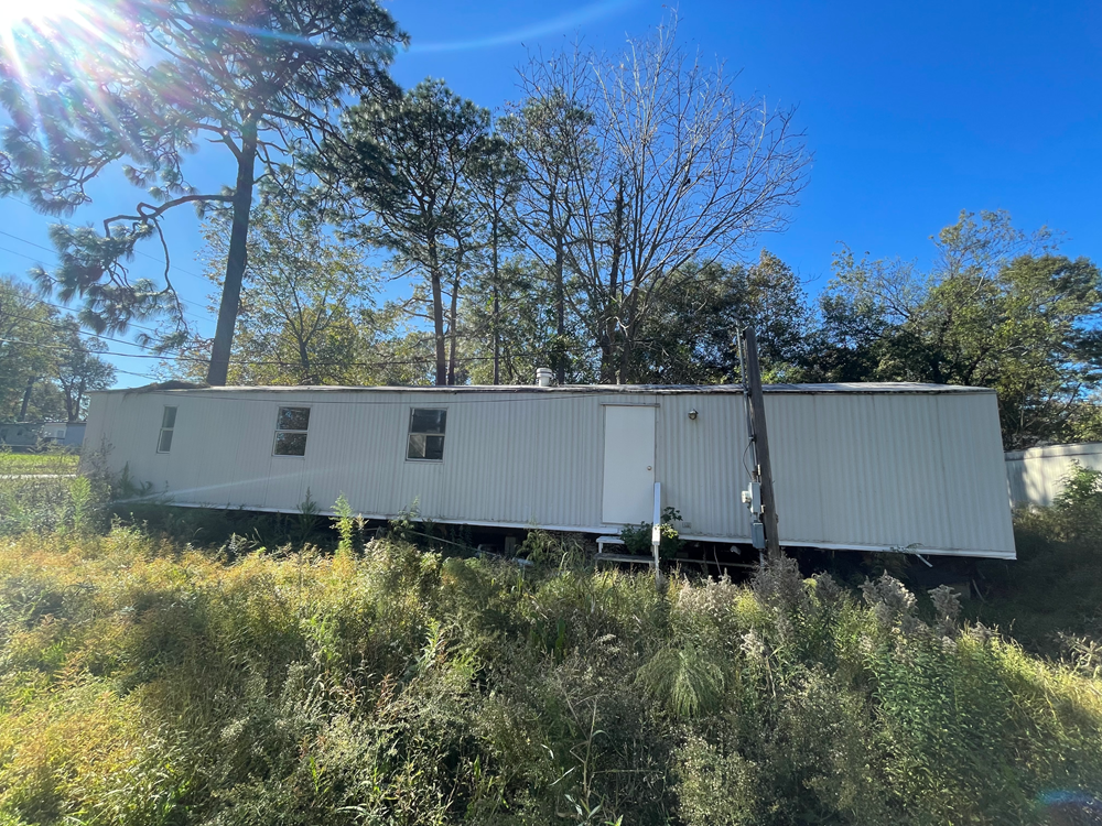 A white building is surrounded by greenery and trees.