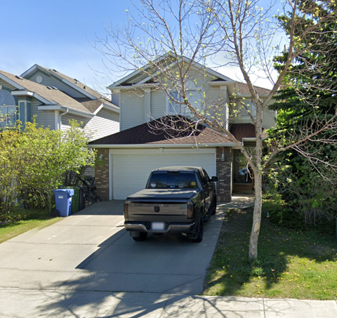 A black truck is parked in front of a house.
