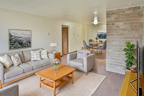 A living room with a grey couch, a wooden coffee table, and a painting on the wall.
