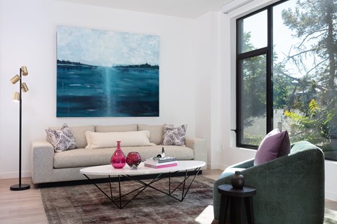 A living room with a couch, a coffee table, and a painting on the wall.