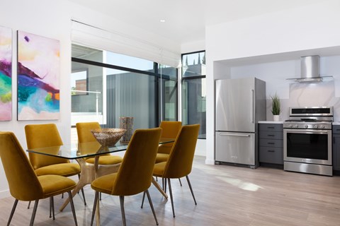 A modern kitchen with yellow chairs and a glass table.