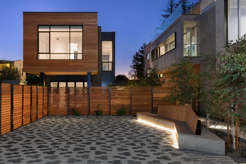A modern house with a wooden fence and a stone patio.