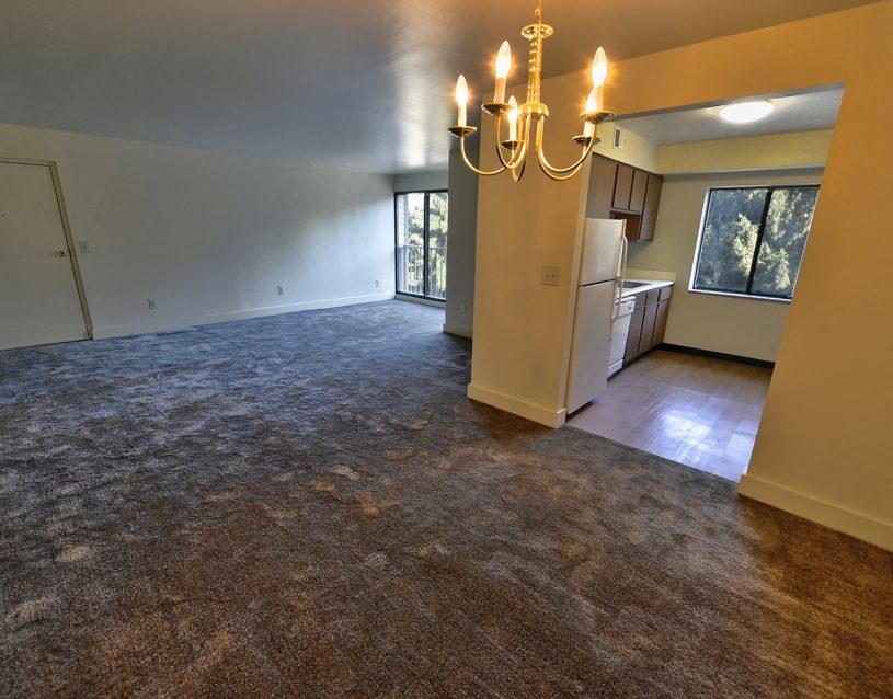 an empty living room and kitchen with a chandelier