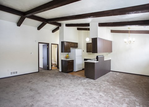 A spacious living room with a kitchen area in the background.