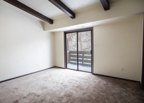 A room with a carpeted floor and a sliding glass door.